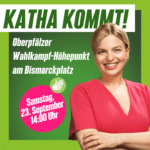 Titel in Großbuchstaben: Katha Kommt! Darunter zu sehen die bayerische Spitzenkandidaten der Grünen Katharina Schule. Sie trägt ein rotes Kleid und lächelt.